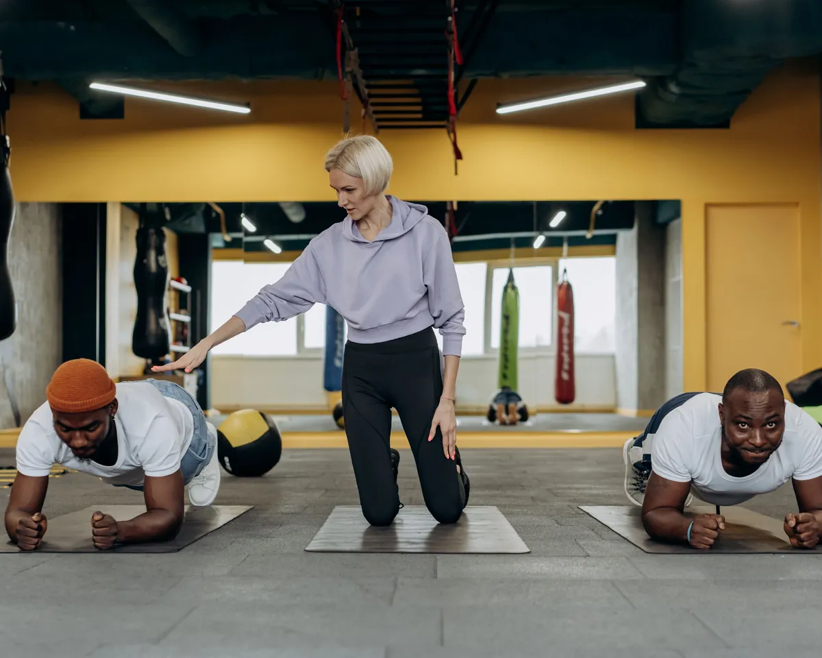 Coach correcting form during a small group plank session